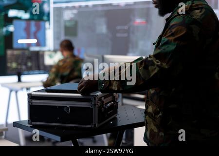 Military staff in a high tech command post gathers intelligence for crucial defense operation, working with satellite radar systems on computers. Supporting troops in field missions. Stock Photo
