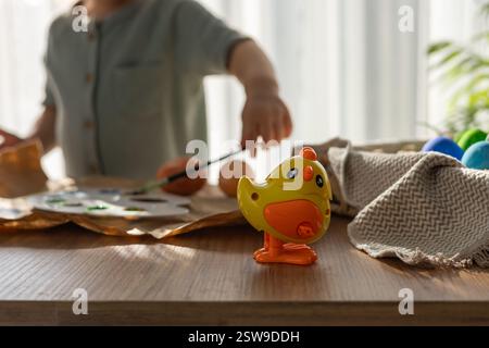 Toy Yellow Hen on the Background of Easter Eggs and a Child with brush. Springtime celebration. Concept of childhood, happiness, familys weekend, frie Stock Photo