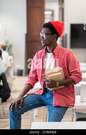 Black student guy looking out of window thinking about weekend plans while studying in library Stock Photo
