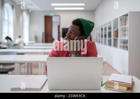 Pensive Black student man looking into distance while studying in library, disinterested in study Stock Photo