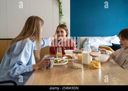 Happy caucasian family mother and two kids talking and smiling while having breakfast together Stock Photo