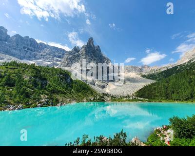 Turquoise lake in the Dolomites, framed by mountains and reflecting summer skies Stock Photo