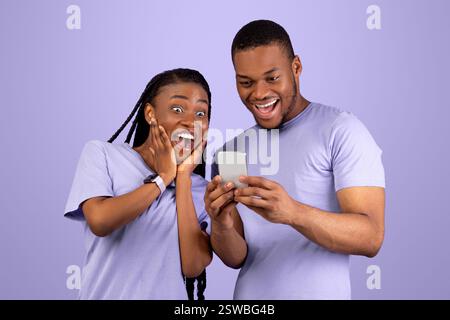 Portrait of surprised black couple using smartphone Stock Photo