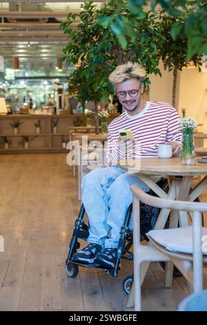 Smiling dreamy freelancer man drinking coffee at cafe table, using mobile phone. Coffee break. Stock Photo