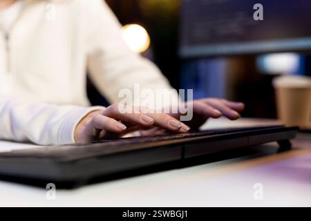 IT operator working from home developing software in JavaScript programming language using PC. Close up shot of system engineer in apartment writing lines of code on computer using keyboard Stock Photo