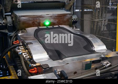Industrial machinery forming carbon fiber with a bright green laser light showcasing precision and technology Stock Photo