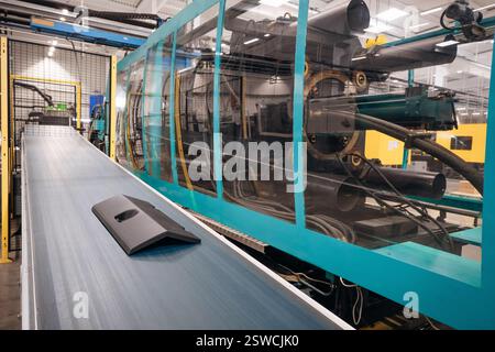 Industrial plastic part on a conveyor belt after the molding process Manufacturing of an industrial part Stock Photo