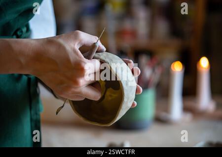 Female hands of potter shape bowl from white clay in pottery workshop. Pottery skills, manual labor Stock Photo