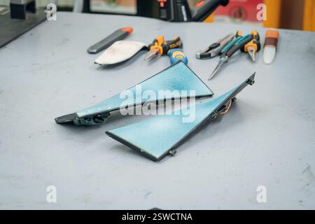 Blue triangle fragments and various hand tools arranged on a neutral colored work surface in a workshop Stock Photo