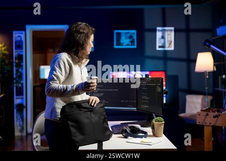Admin with disposable cup of coffee entering office to implement security measures, protecting company systems and data. IT staff member starting job shift, testing and debugging code Stock Photo