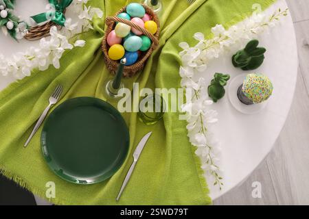 Festive table serving with painted eggs, flowers and cake for Easter celebration, top view Stock Photo