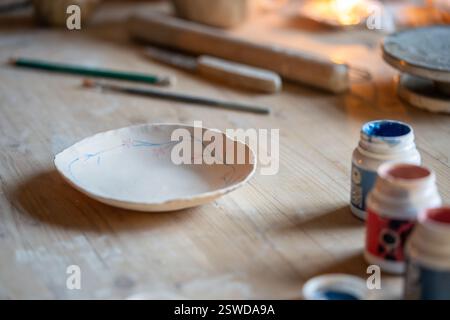 Ceramic painted plate with flower design pattern on wooden table. Pottery workshop, tableware sales Stock Photo