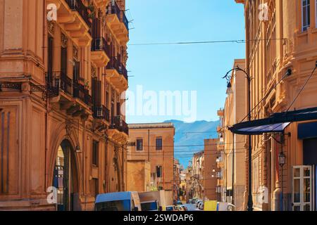 Picturesque street in Palermo, Italy, with historic buildings featuring ornate balconies and architectural details. Street with mountains in the backg Stock Photo