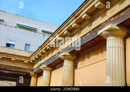 Section of building with classical architectural elements, fluted columns with capitals and a detailed entablature featuring dentil. Ancient Greek and Stock Photo