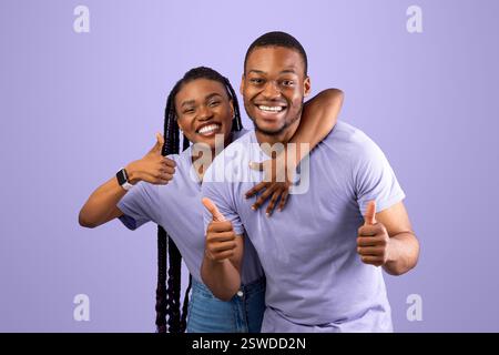 Happy black couple gesturing thumbs up and smiling Stock Photo