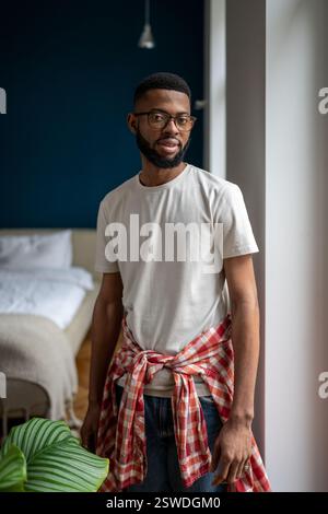 Domestic portrait of bearded African American guy in casual clothes standing in modern apartment Stock Photo