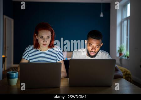Focused workaholic couple of freelancers work on laptops at home Stock Photo