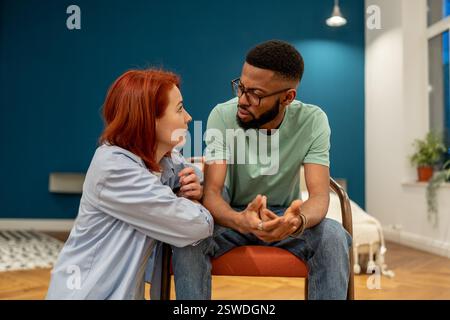 Unhappy serious interracial couple young man and woman talking about relationships at home Stock Photo
