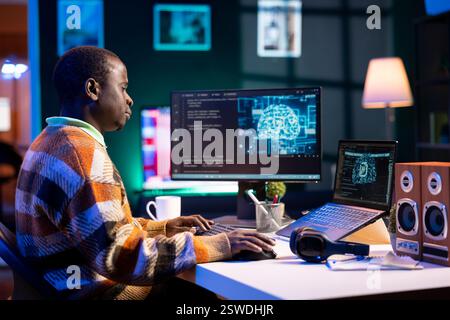 African american man working on computer to write code and programming in artificial intelligence and deep learning. Male IT engineer using pc to ensure cyber security, neural network. Stock Photo
