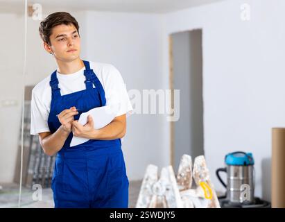 Young foreman making task list during works in building under construction Stock Photo