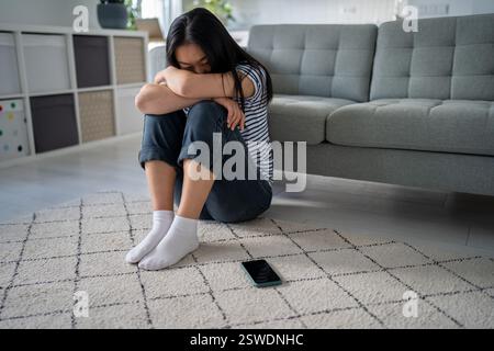 Lonely sad asian woman suffering on floor looks devastated mental trouble bad relationship breakup. Stock Photo