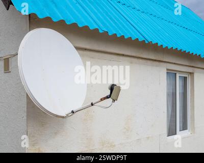 Satellite dish at home roof installed, close up. Stock Photo