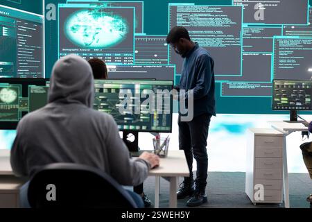 Governmental hackers analyzing data for cyber threat detection, looking at a big screen in high tech office. Highlight cyber intelligence, online security and prevention of digital threats. Stock Photo