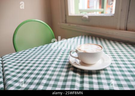 Warm cup of coffee on a checkered tablecloth in a cozy cafe Stock Photo