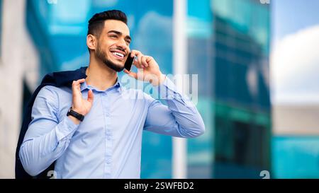 Happy muslim entrepreneur going home from job, talking on cellphone Stock Photo