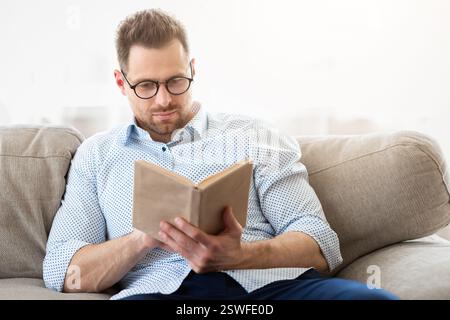 Handsome man reading a book at home Stock Photo