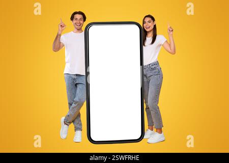 Couple standing next to big white empty smartphone screen Stock Photo