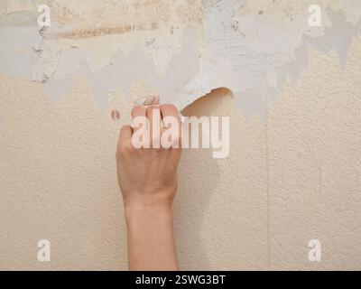 Hand removes old wallpaper from the wall. The concept of repair. Stock Photo