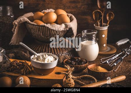 Assorted baking ingredients on wooden vintage table, brown colors. Preparation for home baking. Stock Photo