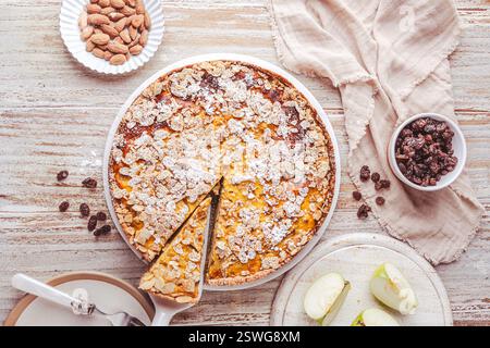 Homemade apple and almond cake, raisins and other ingredients, on white wooden background, top view Stock Photo