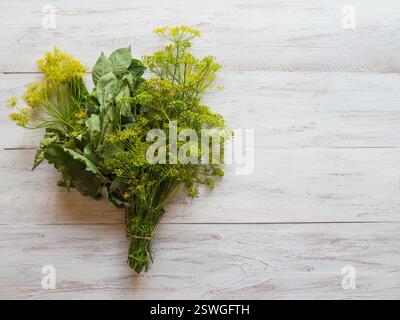 A bouquet of spices for pickling. Green spices for preserving vegetables on a white wooden table. Stock Photo