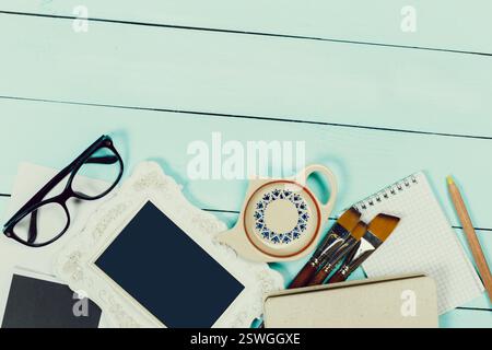 Creative workspace setup featuring tools, stationery, and decorative items on a light blue wooden surface Stock Photo