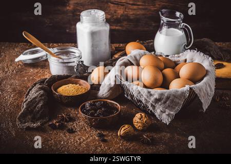 Assorted baking ingredients on wooden vintage table, in brown tone. Preparation for home baking. Stock Photo