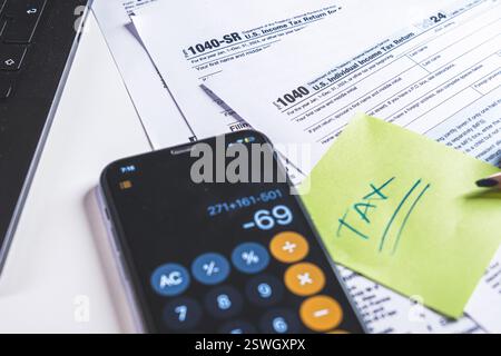 Accountant calculating taxes using calculator app on smartphone Stock Photo