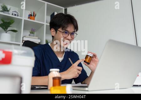 Medical student studying and analyzing medications at a desk with a laptop and notepad. Stock Photo