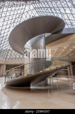 Paris, France - 02 23 2022: Louvre museum. The grand spiral staircase and elevator under the Louvre pyramid in the Reception Hall Stock Photo