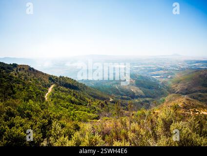 lush green valley, hills, mountains, clear blue sky. Dirt path Stock Photo