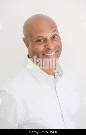 Smiling man in a striped shirt posing against a white background Stock Photo
