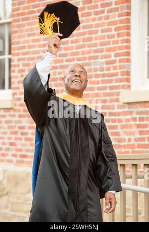 Graduate joyfully raising cap in celebration of achievement Stock Photo