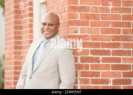 Stylish professional smiling warmly against a brick backdrop Stock Photo