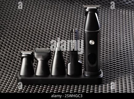 Set of modern electric trimmer with attachments for beard, ears and nose on a black background, close-up, hairdressing Stock Photo