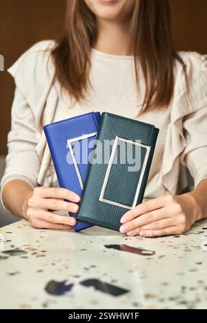 Female presenting elegant wallets in blue, green leather minimal design modern stylish accessories concept Stock Photo