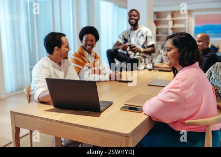 A dynamic group of advertising agency coworkers enjoying a collaborative discussion. Diverse team members sharing ideas and fostering creativity aroun Stock Photo