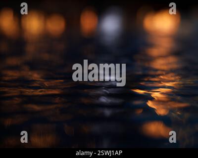 reflections of lights on rippled water at night Stock Photo