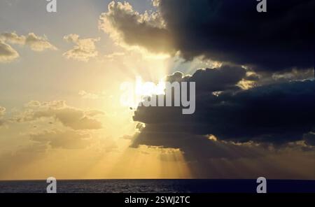 Dark dramatic sky with sunlight rays over sea. Persian Gulf. The sky is cloudy and the sun is shining through the clouds. Stock Photo