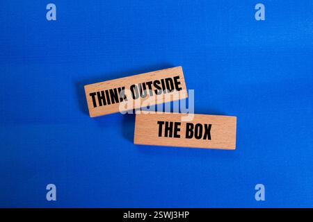 Think outside the box message written on wooden blocks on blue background. Conceptual think outside the box symbol. Copy space. Stock Photo
